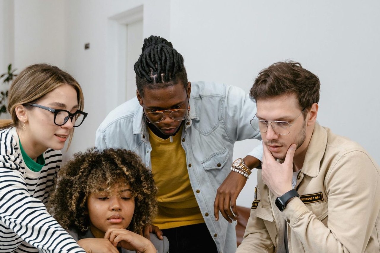 Diverse group of coworkers collaborating on a project using a laptop in a modern office.